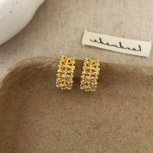 Detail shot of rectangular gold earrings with hammered texture on a paper tray