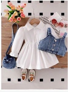 Flat lay of baby girl outfit with white puff sleeve dress and denim vest plus accessories