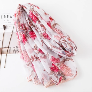 Détail d'une écharpe florale avec bordure en dentelle rose et texture douce en coton-lin