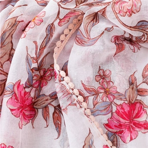 Détail d'une écharpe rose en coton et lin avec imprimé floral et dentelle