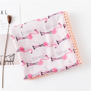 Détail d'une écharpe en coton rose avec motifs flamants et bordure de pompons