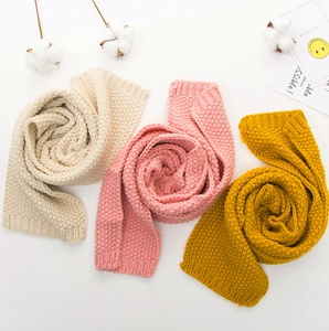Detail of soft knitted baby scarves in cream, pink, and yellow with thick ribbed texture