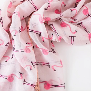 Détail d'une écharpe en coton rose avec imprimé flamant rose et bordure à pompons