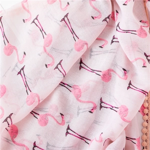Détail d'une écharpe en coton et lin rose avec motif flamant rose et franges à pompons