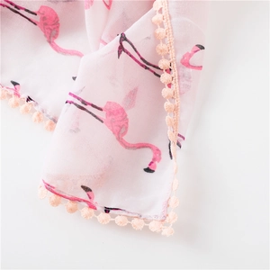 Détail d'une écharpe rose avec motifs flamants et bordure de pompons décoratifs