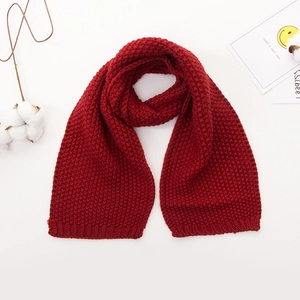 Detailed view of red chunky knit baby scarf with soft warm texture and decorative cotton branch