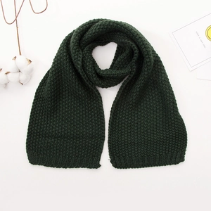 Detail of dark green chunky knit baby scarf with decorative cotton branch on white background