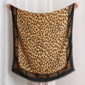 Detail of leopard print scarf with black borders, cool lettering and fringe edges