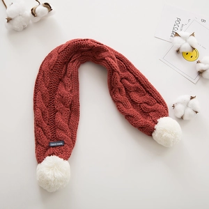 Détail d'une écharpe en maille rouge pour enfant avec pompon blanc et étiquette Hand made