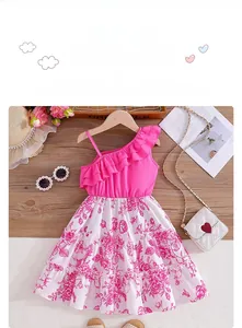Detail of pink floral toddler dress with one-shoulder ruffle design on wood background