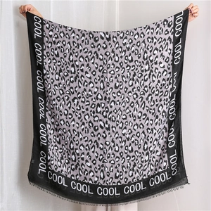 Macro view of leopard print shawl with fringe edges and COOL typography detail