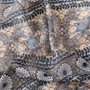 Détail de l'imprimé floral ethnique sur une écharpe légère en coton et lin avec pompons