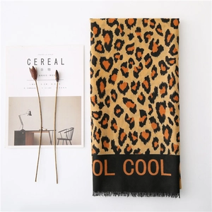 Leopard print scarf with orange COOL lettering and fringe edges on minimalist background