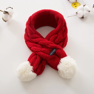 Détail de l'écharpe en maille rouge pour enfants avec pompons blancs et étiquette