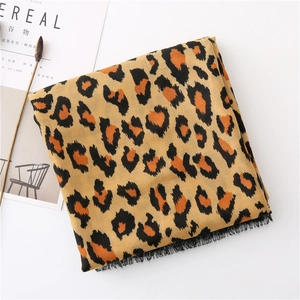 Close-up of leopard print scarf with black fringe tassels on a minimalist background