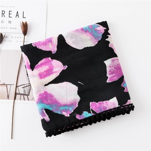 Vue à plat d'une écharpe florale noire avec imprimés colorés et détails de pompons