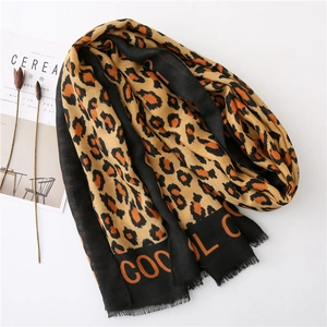 Detail of leopard print scarf featuring raw fringe edges and decorative COOL lettering