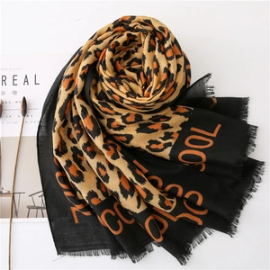 Close-up of leopard print scarf with orange COOL lettering and frayed fringe edges