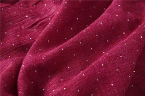 Detailed macro view of dark red cotton linen fabric with fine pleats and silver rhinestones
