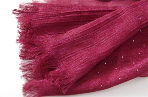 Macro detail of wine red linen scarf with sparkling rhinestones and fringe edges