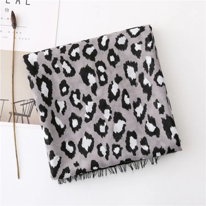 Detail of grey leopard print scarf featuring black fringe tassels on a minimalist background