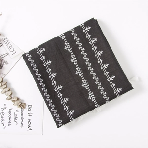 Detail of black cotton linen scarf featuring white star patterns and fringe edges
