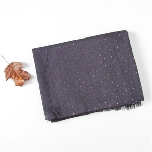 Detail of dark purple-gray linen shawl featuring white polka dots and fringed edges