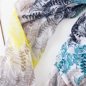 Détail du foulard en coton lin à imprimé plumes avec bordure de pompons verts