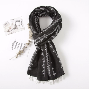 Detail of black cotton linen scarf with white geometric embroidery and tassel fringe