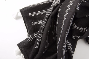 Detail of black cotton linen scarf showing white cross patterns and fringe decorative tassels