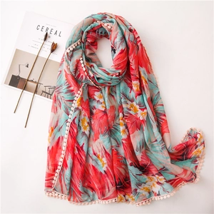Détail d'un foulard en lin à motifs floraux rouges avec des bordures à pompons beige
