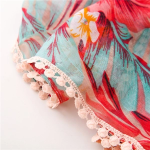 Détail d'une écharpe à fleurs tropicales avec une bordure en dentelle à pompons crème