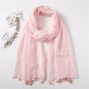 Detail of pink cotton linen scarf featuring white floral patterns and delicate tassels