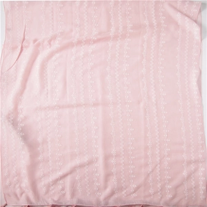 Detailed view of pink cotton linen shawl featuring white embroidery and fringe tassels