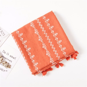 Detail of orange cotton linen scarf with white embroidery and matching tassels