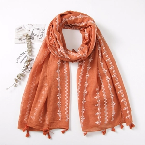 Detail of orange cotton linen scarf with white geometric patterns and handmade tassels