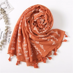 Detail of terracotta linen scarf with white cross stitching and fringe tassels