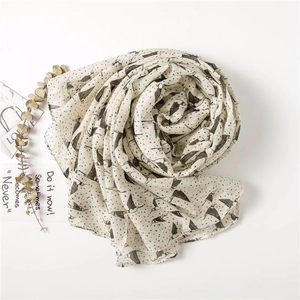 Détail d'oiseaux noirs et de pois sur un tissu de foulard léger de couleur crème