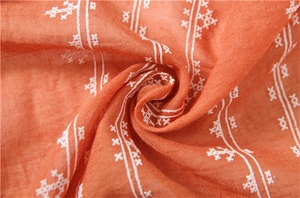 Detailed macro view of cotton linen scarf with white embroidery and terracotta fabric