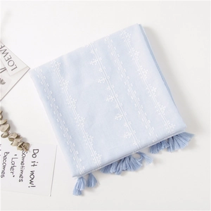 Detail of light blue cotton linen scarf featuring white embroidery and fringe trim