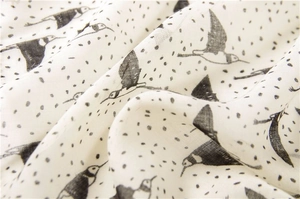Gros plan sur le tissu doux en coton avec motifs d'oiseaux et pois noirs sur fond écru