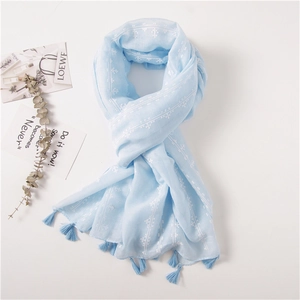 Detail of light blue cotton linen scarf with white star embroidery and tassels
