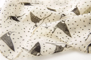Gros plan d'une écharpe légère avec imprimés de pies et texture à pois noirs