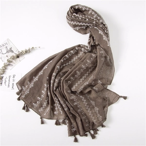 Detail of dark brown linen scarf featuring white ethnic embroidery and fringe edges