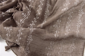 Close-up of brown cotton linen scarf featuring white embroidery details and tassel edges