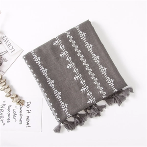 Detailed embroidery of white cross stars on dark gray linen scarf with handmade tassels