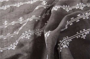 Detailed close-up of dark grey cotton linen scarf with white floral embroidery