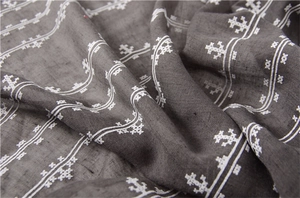 Detail of dark grey cotton linen scarf with white wave embroidery and floral patterns