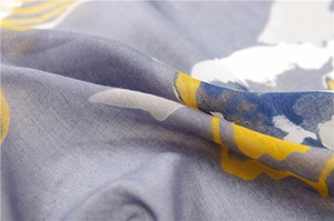 Macro shot of grey linen scarf with abstract yellow print and woven fabric texture