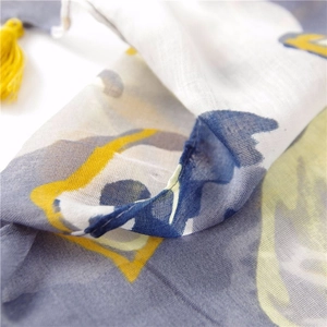 Detailed close-up of gray cotton scarf with yellow tassel edge and geometric printing